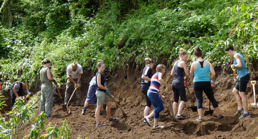 Service learning group from Québec flattening a section of hill for a new dormitory.